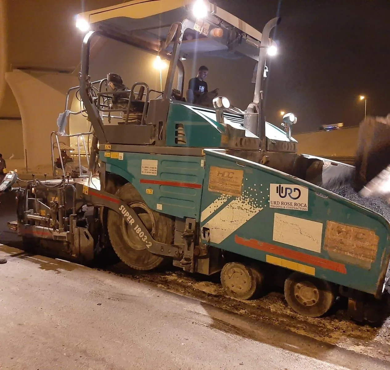 Paving train in operation — continuous night asphalt laying